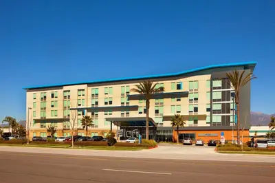 a large building with palm trees in front of it at Aloft Ontario-Rancho Cucamonga in Rancho Cucamonga