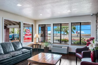 a living room with a couch and a table and windows at Red Roof Inn Palmdale - Lancaster in Palmdale