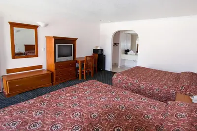 a hotel room with two beds and a flat screen tv at West Coast Inn Santa Ana in Santa Ana