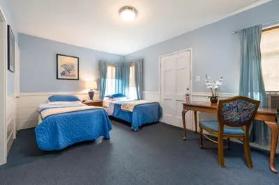 a bedroom with two beds and a desk and a table at Wilshire Motel in Los Angeles
