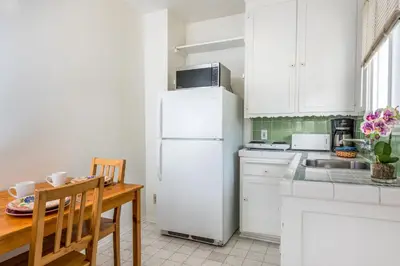 a white kitchen with a table and a refrigerator at Wilshire Motel in Los Angeles