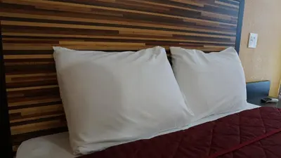 two white pillows on a bed with a wooden headboard at Holly Crest Hotel - Los Angeles, LAX Airport in Inglewood