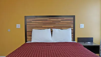 a bedroom with a bed with a wooden headboard and white pillows at Holly Crest Hotel - Los Angeles, LAX Airport in Inglewood