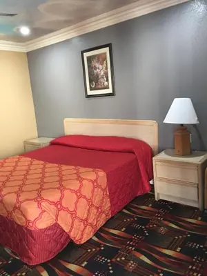 a bedroom with a bed with a red comforter at Budget Inn LAX-Lawndale in Lawndale