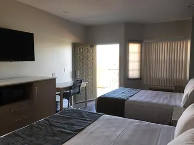 a hotel room with two beds and a desk and a television at Cali Inn in Carson