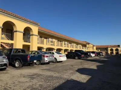 a group of cars parked in a parking lot in front of a building at Cali Inn in Carson