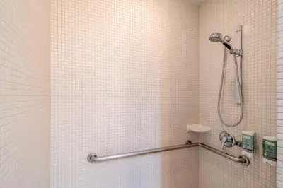 a shower in a bathroom with white tiles at Best Western At Ventura Pier in Ventura