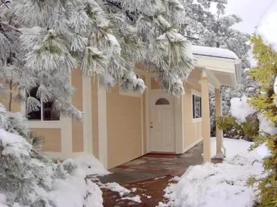 a house with a white door in the snow at Giant Oaks Lodge in Running Springs