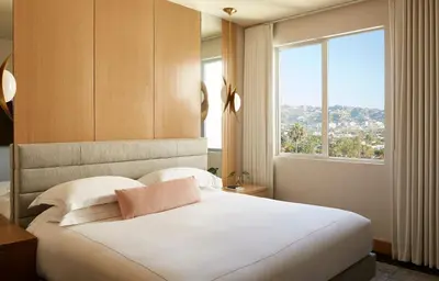 a bedroom with a large white bed with a window at Kimpton Hotel Wilshire by IHG in Los Angeles