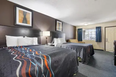 a hotel room with two beds and a chair at Economy Inn Barstow in Barstow