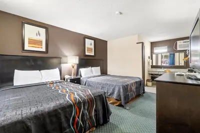 a hotel room with two beds and a sink at Economy Inn Barstow in Barstow
