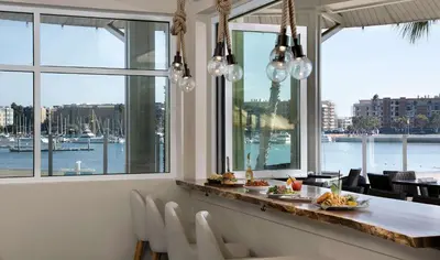 a dining room with a view of the water at Jamaica Bay Inn Marina Del Rey Tapestry Collection by Hilton in Los Angeles
