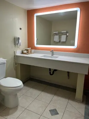 a bathroom with a toilet and a sink with a mirror at Rivera Inn & Suites Motel in Pico Rivera