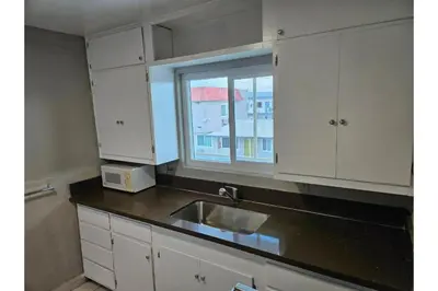 a kitchen with white cabinets and a sink and a window at Hotel Ridgecrest An Extended Stay Studio in Ridgecrest