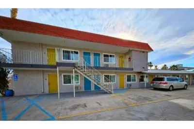 a building with a car parked in a parking lot at Hotel Ridgecrest An Extended Stay Studio in Ridgecrest