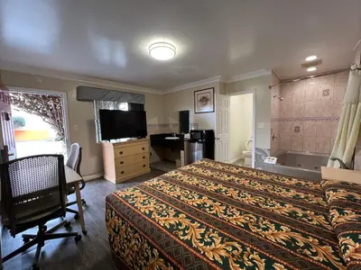 a bedroom with a bed and a television and a tub at Flamingo Motel Oxnard in Oxnard