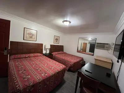 a hotel room with two beds and a desk at Flamingo Motel Oxnard in Oxnard