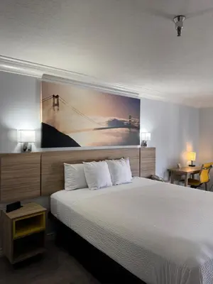 a bedroom with a large bed with a painting on the wall at Days Inn by Wyndham Near City Of Hope in Duarte