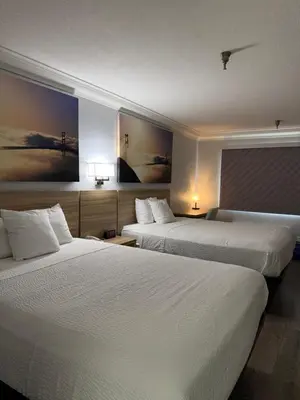 a hotel room with two beds and paintings on the wall at Days Inn by Wyndham Near City Of Hope in Duarte