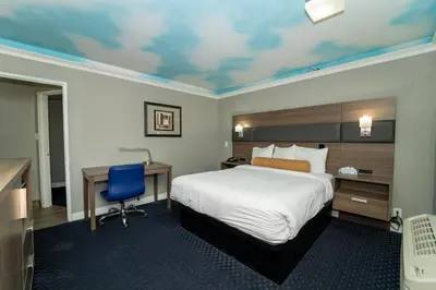 a hotel room with a bed and a desk and a bed sidx sidx at Hollywood Palms Inns & Suites in Los Angeles