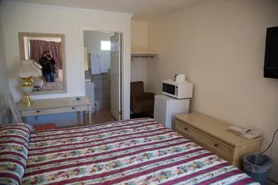 a hotel room with a bed and a person in the mirror at Boron Motel in Boron