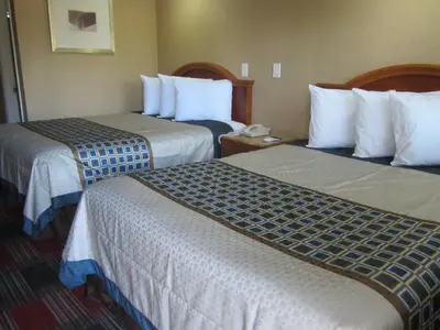 a hotel room with two beds with white sheets at Little Boy Blue Motel in Anaheim