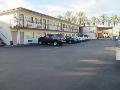 a parking lot in front of a building with cars at Little Boy Blue Motel in Anaheim