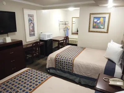a hotel room with two beds and a desk at Little Boy Blue Motel in Anaheim