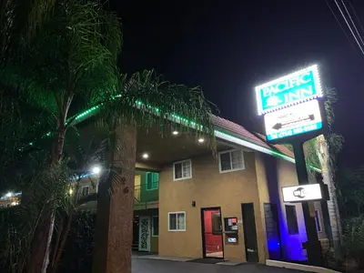 a hotel inn with a neon sign at night at Pacific Inn Anaheim in Anaheim