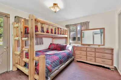 a bedroom with bunk beds and a dresser and a mirror at Lodge House-Family Cabin with Pool Table by Big Bear Vacations in Big Bear Lake