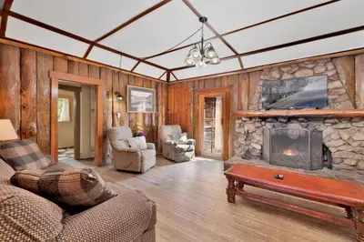 a living room with a stone fireplace and a couch at Lodge House-Family Cabin with Pool Table by Big Bear Vacations in Big Bear Lake