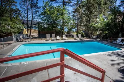 a swimming pool with a wooden fence around it at Lupine Lakeside Resort Cabin by Big Bear Vacations in Big Bear Lake
