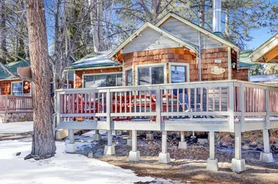 a log cabin with a large deck in the snow at Lonepine Lakeside Resort Retreat by Big Bear Vacations in Big Bear Lake
