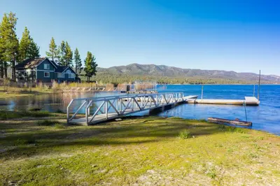 a dock on a lake with a house in the background at Sunrise Lakefront Family Cabin by Big Bear Vacations in Big Bear Lake