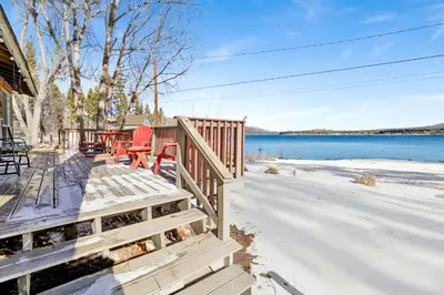 a house with a deck with a view of the water at Sunrise Lakefront Family Cabin by Big Bear Vacations in Big Bear Lake