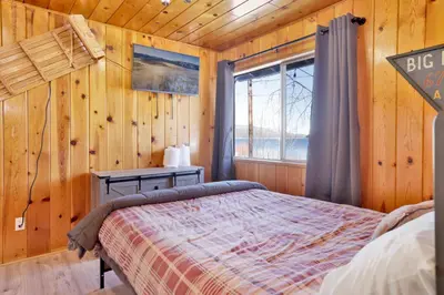 a bedroom with a bed and a window in a cabin at Sunrise Lakefront Family Cabin by Big Bear Vacations in Big Bear Lake