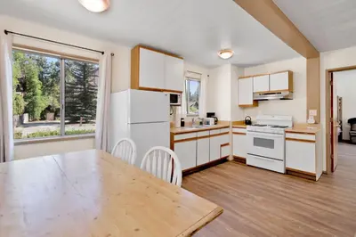 a kitchen with white appliances and a wooden table at Twin Pines Family Cabin by Big Bear Vacations in Big Bear Lake