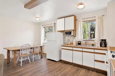 a kitchen with a table and a white refrigerator at Twin Pines Family Cabin by Big Bear Vacations in Big Bear Lake