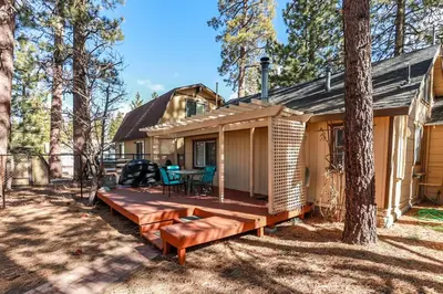 a cabin in the woods with a large wooden deck at Pines 23-1438 by Big Bear Vacations in Big Bear Lake