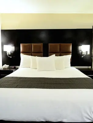 a bedroom with a large white bed with a black headboard at Days Inn by Wyndham Downey in Downey