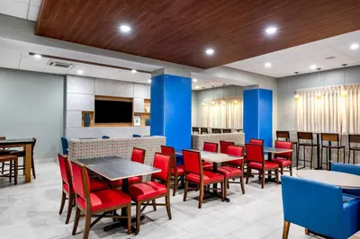 a dining room with tables and red chairs at Holiday Inn Express & Suites Santa Ana - Orange County by IHG in Santa Ana
