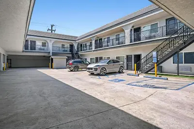 two cars parked in a parking lot in front of a building at Hyland Inn Long Beach in Long Beach