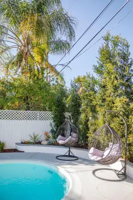 two swing chairs next to a swimming pool at Enchanting Sherman Oaks Home With Pool permit #HSR two five zero zero 3222 in Sherman Oaks