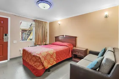 a hotel room with a bed and a couch at Sky Palm Motel - Orange in Orange