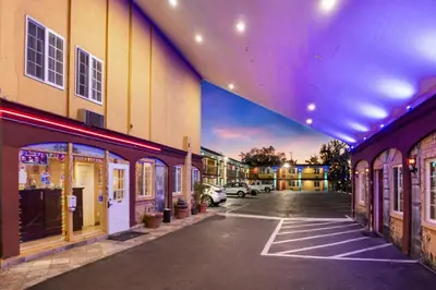 an empty parking lot next to a building with purple lights at Sky Palm Motel - Orange in Orange