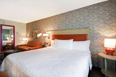 a hotel room with a large white bed and a brick wall at Home2 Suites by Hilton Victorville in Victorville