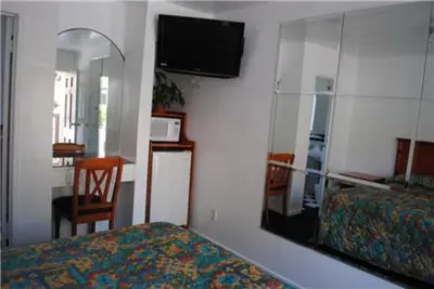 a bedroom with a mirror and a bed and a chair at Rose Bowl Motel in Los Angeles