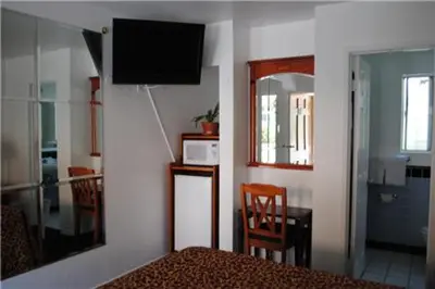 a bedroom with a bed and a television on a wall at Rose Bowl Motel in Los Angeles