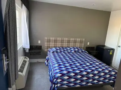 a bedroom with a bed with a blue and white comforter at Vista Motel in Los Angeles