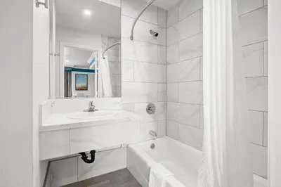 a white bathroom with a sink and a bath tub at Rodeway Inn Commerce - Los Angeles in Commerce